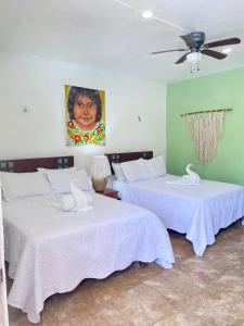 two beds in a room with a painting on the wall at Pelican Inn at Las Dunas Chelem in Chelem +36 photos