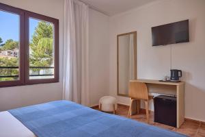 a bedroom with a bed and a desk and a window at Hotel Navia Santa Ponsa - Adults Only in Santa Ponsa