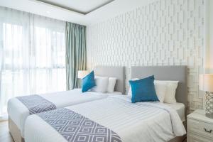 two beds in a hotel room with blue pillows at Seavale patong phuket in Patong Beach
