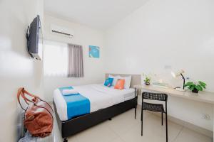 a bedroom with a bed and a desk with a chair at Sans Vibes Hotel Malabar in Bandung