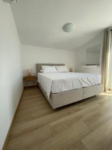 a white bedroom with a large bed and a wooden floor at MyLiving in Kardamaina