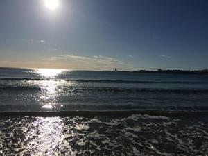 a beach with the sun shining on the water at Hotel Vela Velo Club Vieste in Vieste