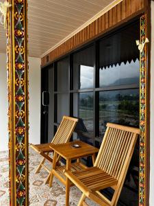 two chairs and a table on a porch with a window at Sun Grace Villa and Camp in Sembalun Lawang +6 photos