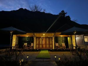 a house with chairs and umbrellas at night at Sun Grace Villa and Camp in Sembalun Lawang