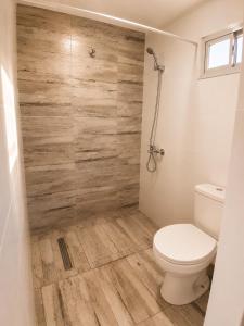 a bathroom with a toilet and a wooden wall at Alta Vista in Villa Yacanto +6 photos