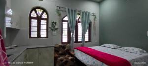 a bedroom with a bed and two windows at Rawat Homestay in Rishīkesh