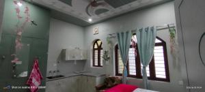 a kitchen with green and white walls and windows at Rawat Homestay in Rishīkesh