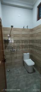 a bathroom with a toilet and wooden walls at Rawat Homestay in Rishīkesh