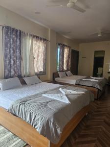 two beds in a bedroom with windows at Hampi Rock-Inn in Hampi +7 photos