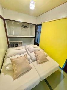 a room with two beds and a yellow wall at 結莉の宿 高槻 in Takatsuki +11 photos