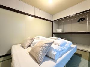 a bed with white sheets and pillows in a room at 結莉の宿 高槻 in Takatsuki