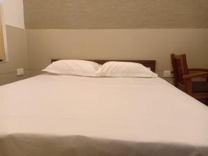 a large white bed with two pillows and a chair at LEMON RESIDENCY By Chungath in Trichūr