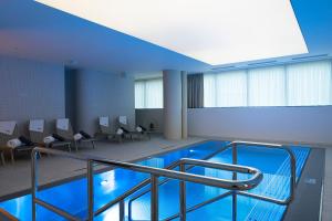 a large room with a swimming pool with chairs at Hotel SOREA MORAVA in Tatranská Lomnica