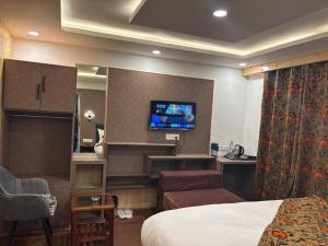 a hotel room with a bed and a flat screen tv at The Cedar Pahalgam in Pahalgām +2 photos
