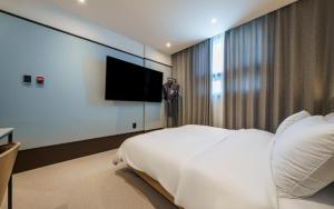 a bedroom with a white bed and a flat screen tv at Daegu Brown Dot Hotel Kyungpook National University in Daegu