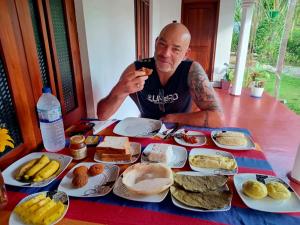 a man sitting at a table full of food at Sigiriya Hidden Home Stay in Sigiriya