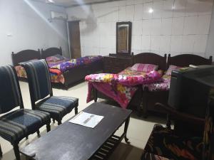a room with four beds and a table and chairs at Hotel Melodyinn in Gujrāt +2 photos