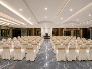 a large room with white chairs and a stage at Hotel Aston Residency in Kolkata