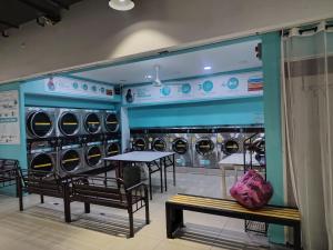 a laundry room with tables and chairs and machines at Suria jaya studio condo shah alam in Shah Alam