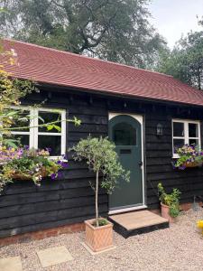 a black house with a green door and flowers at Park Cottage cabin in Bix +9 photos