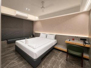 a bedroom with a large white bed and a desk at Hotel Aston Residency in Kolkata