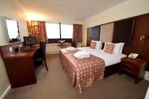 a hotel room with a bed and a desk with a laptop at Normandy Hotel (Near Glasgow Airport) in Paisley