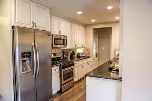a kitchen with white cabinets and a stainless steel refrigerator at Wonderful 4 Bedroom 3 Bath Pool Home 3/4 Mile To Disney in Anaheim