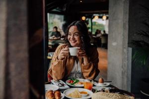 a woman sitting at a table with a cup of coffee at Hyatt Centric Reims in Reims