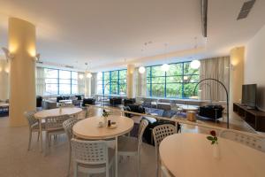 a restaurant with tables and chairs and windows at Hotel SOREA MORAVA in Tatranská Lomnica