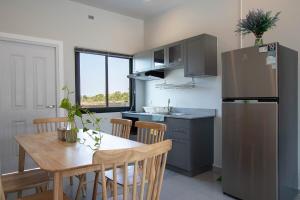 a kitchen with a wooden table and a refrigerator at Pool Villa Maephim 4, by Somjai in Klaeng