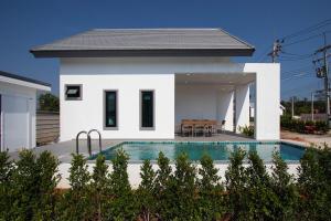 a white house with a swimming pool in front of it at Pool Villa Maephim 4, by Somjai in Klaeng