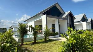 a white house with a swimming pool and palm trees at Pool Villa Maephim 4, by Somjai in Klaeng