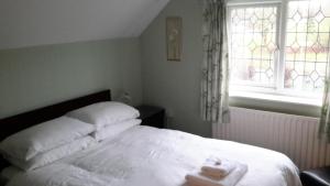 een slaapkamer met een bed met witte lakens en een raam bij The School House in Warrington
