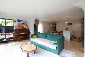 a living room with a blue couch and a piano at The Gentle Stay in Brunoy