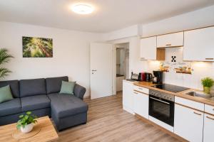a living room with a blue couch and a kitchen at Ferienwohnung Melissa in Unter Feuchten