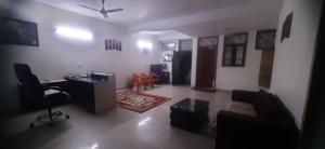 a living room with a couch and a desk at ADA Residency in Noida