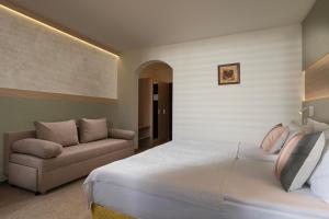 a bedroom with a large bed and a couch at Bile - Family Hotel & Gastro Bar in Beli Osŭm