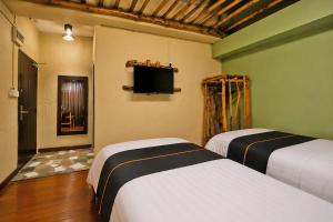 two beds in a room with a tv on the wall at Townhouse Near Tanjung Batu Formerly 900 Inn in Bintulu +44 photos
