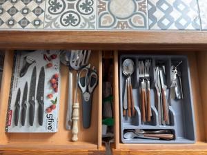 a drawer full of utensils in a wooden cabinet at Le Cocon Loire, 3-room apartment in La Ville-aux-Dames +10 photos