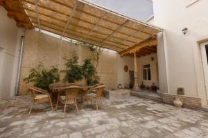 an outdoor patio with a wooden table and chairs at Ismat Premium Guest House in Bukhara +10 photos