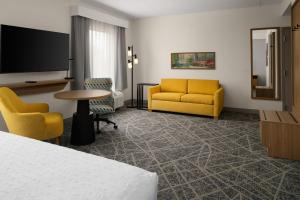 a hotel room with a bed and chairs and a flat screen tv at Hampton Inn & Suites Chadds Ford in Glen Mills