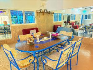 a dining room with a blue table and chairs at Hébergement H in Ngaring