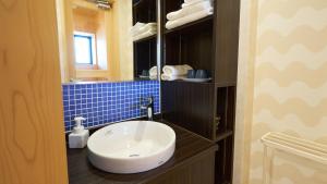 a bathroom with a white sink and blue tiles at Shinwaso Kaishin in Amakusa +78 photos