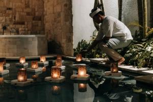 a man lighting candles in a pool of water at Aksari Villa Seminyak by Ini Vie Hospitality in Seminyak