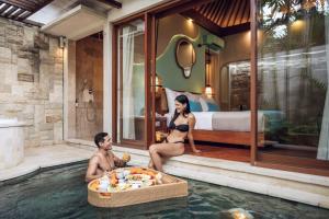 a man and woman sitting in a pool in a hotel room at Aksari Villa Seminyak by Ini Vie Hospitality in Seminyak