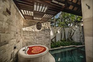 a bath tub filled with red flowers next to a pool at Aksari Villa Seminyak by Ini Vie Hospitality in Seminyak