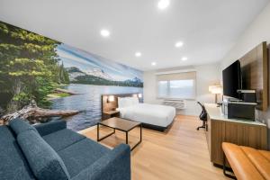 a hotel room with a couch and a bed and a television at Clarion Pointe Kent - Seattle South in Kent