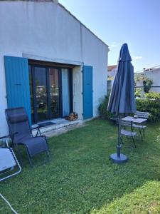 a patio with an umbrella and a table and a chair at Sucré salé in Le Port-des-Barques +4 photos
