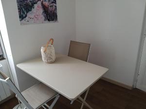 a white table with two chairs and a basket on it at Sucré salé in Le Port-des-Barques