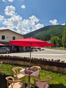 a table and chairs with a red umbrella at Le Guilazur in Château-Ville-Vieille